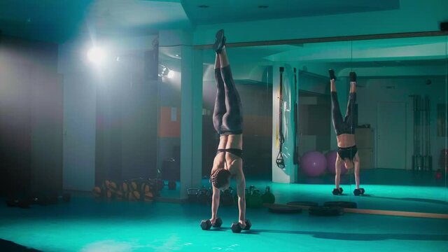 A young fit woman doing a hand stand in the gym