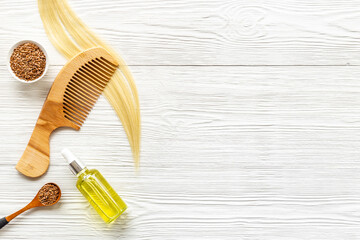 Hair treatment oil with seeds and wooden hair comb. Top view