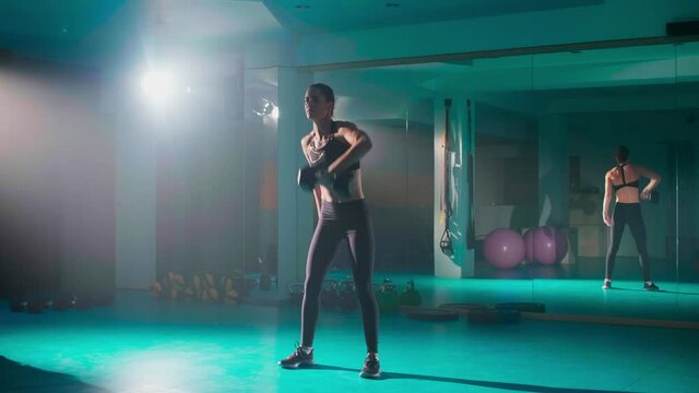 A fit young woman exercising with a dumbbell