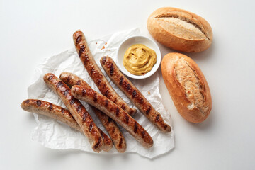 Appetizing sausages and bread placed on white table