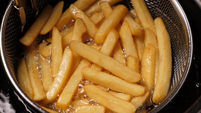Cooking french fries potatoes in deep fryer. Closeup