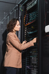 engineer checking wires of server while working in data center