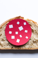 The slice of bread with paper cut out salami.