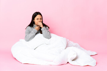 Young mixed race woman wearing pijama sitting on the floor coughing a lot
