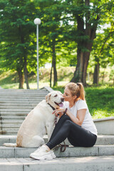 Woman with her dog sitting on stairs in the park. Friendship between pet and owner