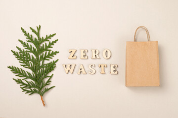 Zero waste concept. View from above. Wooden lettering, paper shopping bag, thuja twig.