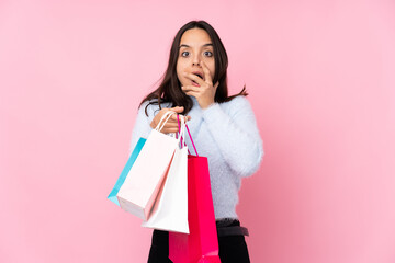 Young woman with shopping bag over isolated pink background surprised and shocked while looking right