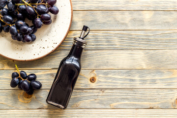 Glass bottle of red wine vinegar with fresh grapes