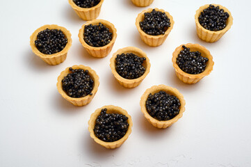 natural black sturgeon caviar in homemade shortcrust pastry tartlets on a white background