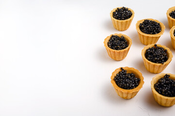 tartlets with natural black caviar on white background, copy space