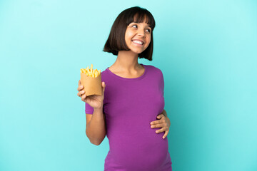 Pregnant woman holding fried chips over isolated background thinking an idea while looking up