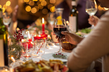 holidays, party and celebration concept - close up of man having christmas dinner at home and drinking red wine