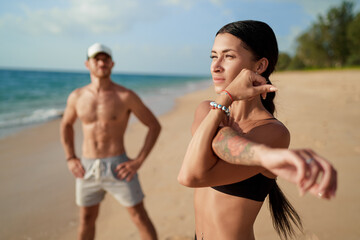 Healthy lifestyle. Young beautiful couple doing sports exercises at the beach.