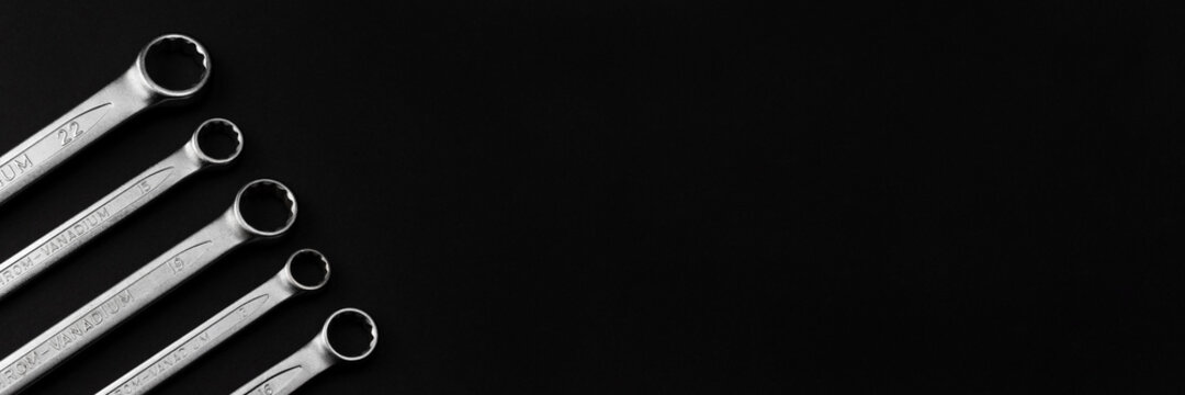 Steel closed end ring wrenches on black background. Wide panoramic banner with copy space