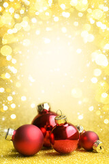 Bright red Christmas balls on gold background with bokeh and falling snow. Merry Christmas and happy New Year