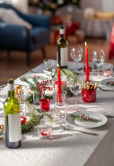 winter holidays, dinner party and celebration concept - christmas table serving with candles, crockery and wine at home