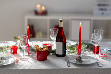 winter holidays, dinner party and celebration concept - christmas table serving with candles, crockery and wine at home