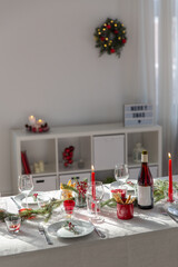 winter holidays, dinner party and celebration concept - christmas table serving with candles, crockery and wine at home