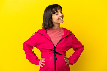 Young pregnant woman over isolated yellow background looking side