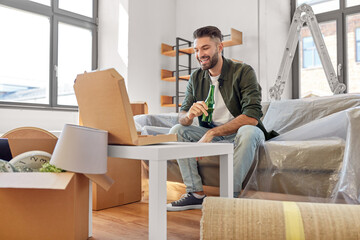 moving, people and real estate concept - happy smiling man with box of pizza and beer bottle at new home