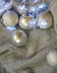 Fototapeta na wymiar gray shiny Christmas balls and a blue garland on a knitted plaid. background for Christmas and New Year. winter holidays.