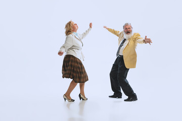 Two retro styled dancers, senior man and woman in vintage attire dancing rock-and-roll isolated on white background