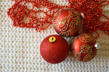 red balls for the Christmas tree and beads for decoration for winter holidays on a white knitted...