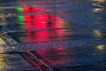 Close-up of wet square at City of Zürich with reflections of green and red lights on a rainy autumn morning. Photo taken November 22nd, 2021, Zurich, Switzerland.