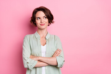 Portrait of attractive curious brown-haired girl folded arms thinking copy space isolated over pastel pink color background