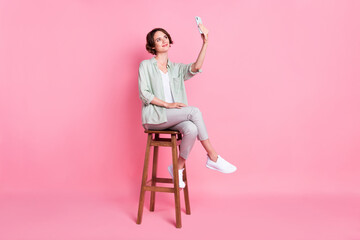 Full length photo of sweet bob hairdo young lady sit do selfie wear grey green look isolated on pink background