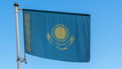National flag of Kazakhstan on a flagpole in front of blue sky with sun rays and lens flare. Diplomacy concept.