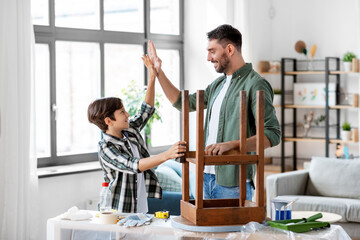 family, diy and home improvement concept - happy smiling father and son restoring old table and...