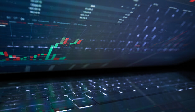 Laptop screen with stock market charts. Technical analysis and fundamental indicators of stock quotes in the trading terminal. Japanese candlesticks and company tickers.