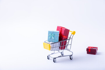 Miniature cart with gifts on a white background. Holidays shopping concept. Close-up.