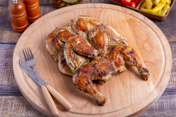 Tapaca (tabaca) chickens with cherry tomatoes and pepperoni on a wooden board. Traditional Georgian dish. Close-up.