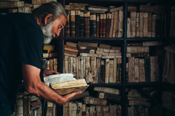 Senior man holding an old book in a library