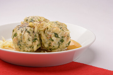 Spinach roll dumplings with brown melted butter on a white plate and white red background