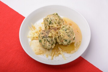 Spinach roll dumplings with brown melted butter on a white plate and white red background
