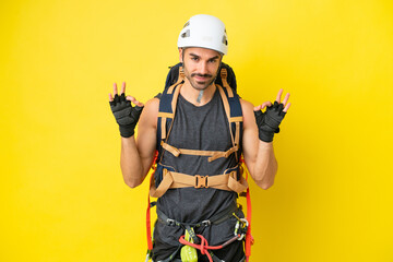 Young caucasian rock climber man isolated on yellow background showing an ok sign with fingers