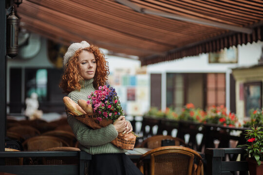 Woman portrait in a beret sweater holding a bouquet of flowers of the restaurant background 