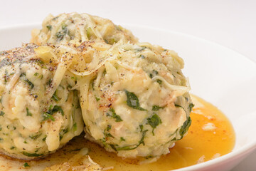Spinach roll dumplings with brown melted butter on a white plate and white red background