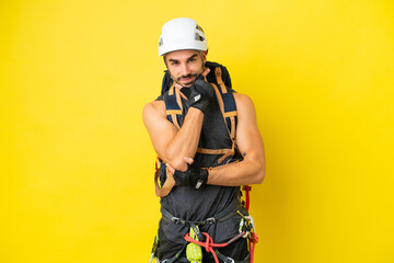 Young caucasian rock climber man isolated on yellow background smiling