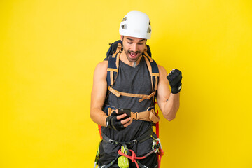 Fototapeta premium Young caucasian rock climber man isolated on yellow background surprised and sending a message