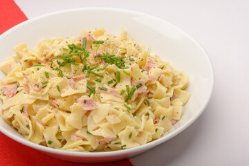 Traditional Austrian Dish so called Schinkenfleckerl on a white plate with red and white background