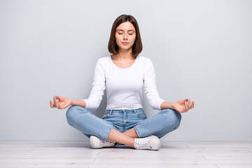 Photo of dreamy peaceful young woman wear white outfit sitting legs crossed practicing yoga smiling...