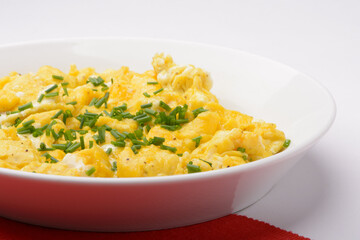 scrambled breakfast eggs on a white plate with red and white background