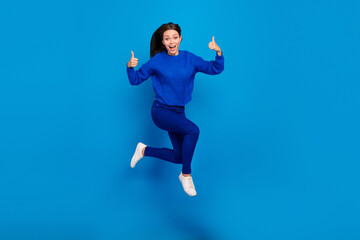 Fototapeta premium Full length body size view of attractive cheerful glad girl jumping running showing thumbup isolated on bright blue color background