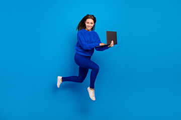 Fototapeta na wymiar Full length body size view of attractive cheery trendy girl jumping using laptop typing isolated on bright blue color background