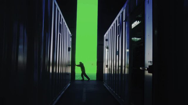 Silhouette of a Warehouse Worker Opening Metal Door with Chroma Key Background. Customize your Background. You can replace your green screen background with any image or video. 4K Resolution.