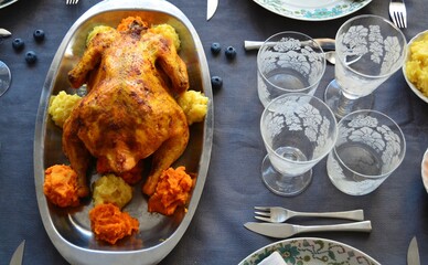 Restaurant table with crystal glasses, roast chicken and salad